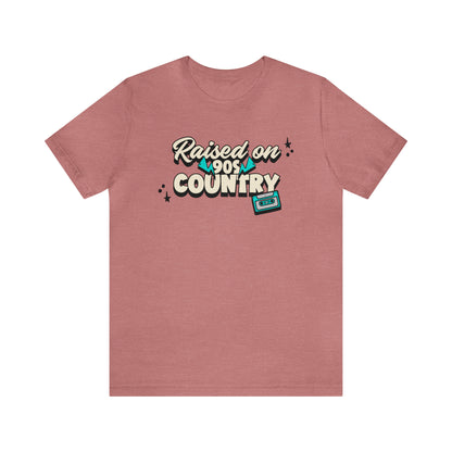  "raised on 90s country" t-shirt in the color heather mauve.